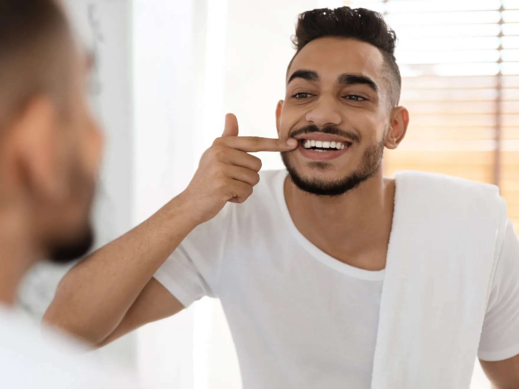 Man smiling while pointing at his teeth